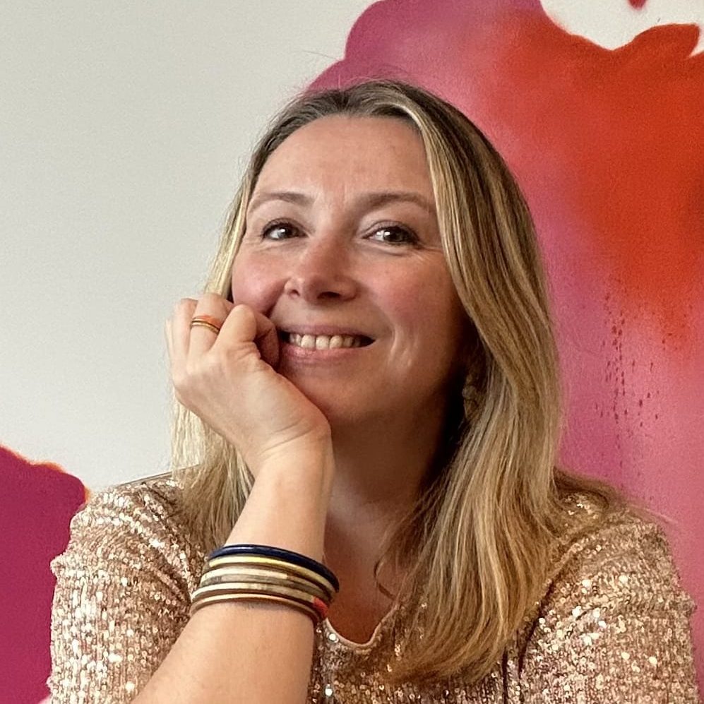 Tiphaine legaud coach de vie et analyste human design Femme souriante avec des cheveux longs, posant devant un fond coloré.
